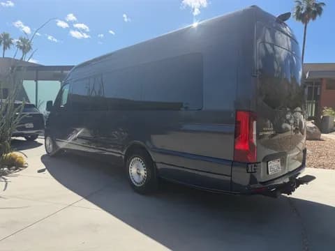 Executive van parked beneath palm trees, rear view